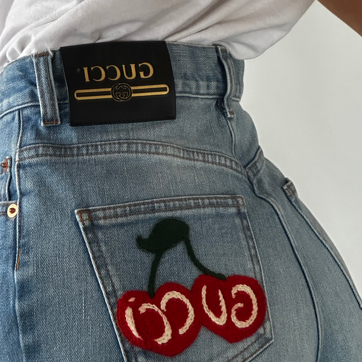 First, a front view of the Gucci Denim Cherry Logo Shorts showcases the signature cherry-knitted logo.